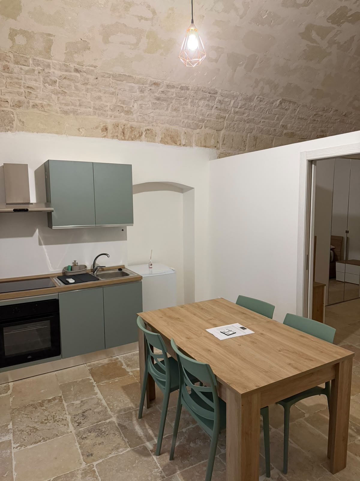 Cucina attrezzata con tavolo da pranzo sotto la volta in pietra